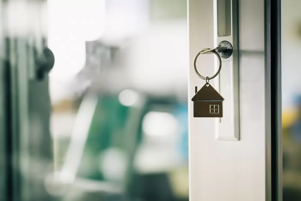 Close-up of house-shaped keychain in front door of home.